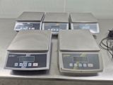four electronic scales sitting on top of a metal counter top