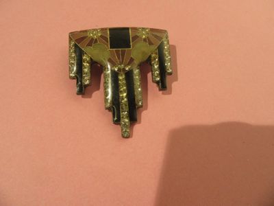 une broche dorée et noire sur un fond rose