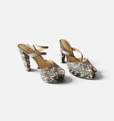 une paire d'escarpins en peau de serpent sur fond blanc