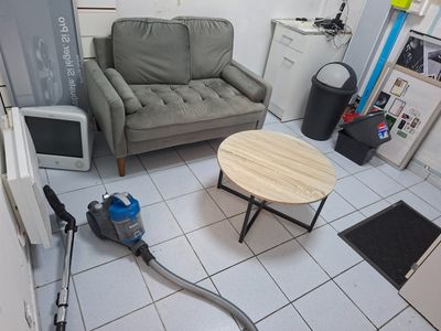 une pièce dans laquelle se trouvent un canapé, une table basse et un aspirateur