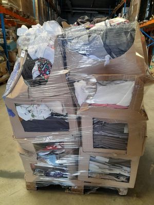 une grande pile de vêtements posée sur une palette dans un entrepôt