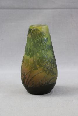 un vase vert et noir posé sur une surface blanche