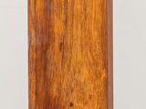 a small wooden clock on a table with a white wall in the background