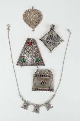 trois bijoux en argent sont exposés sur une surface blanche