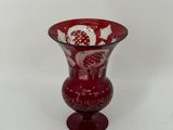 a red glass vase with a white design on it