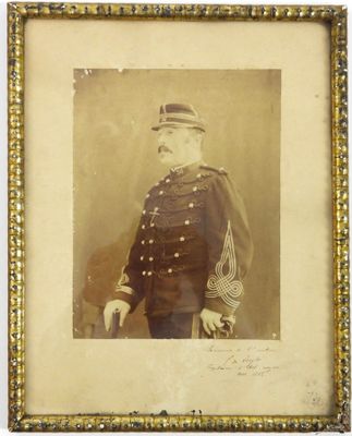une vieille photo d'un homme en uniforme militaire, dans un cadre doré