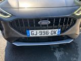 the front end of a grey car with a number plate on it