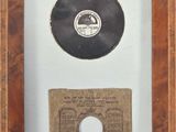 an old record in a wooden frame with a piece of paper underneath it