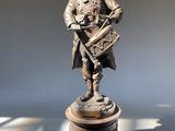 une statue en bronze représentant un homme tenant un fusil