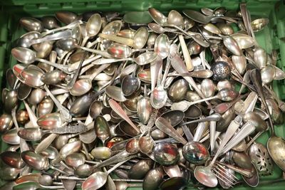 un récipient vert rempli de cuillères et de fourchettes en argent