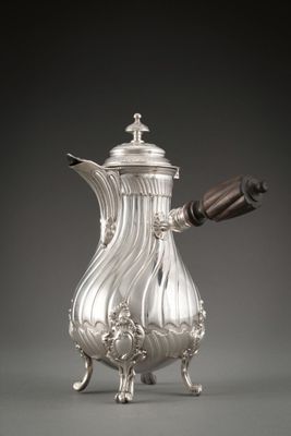 a silver coffee pot with a wooden handle on a stand