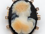 un gros plan sur une broche représentant une femme en robe