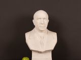 a white bust of a man sitting on a table next to an apple