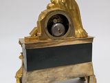 a clock that is sitting on a stand with a statue on it