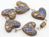 quatre perles de verre bleues et marron en forme de cœur sur un fond blanc