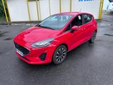 la voiture rouge est garée devant un bâtiment dans un parking