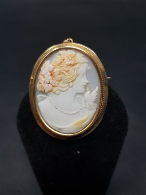 gros plan d'une bague en or avec un camée représentant une femme