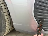 a person holding a measuring tape next to a car