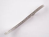 un gros plan d'une broche en forme de barre sertie de diamants posée sur une surface blanche