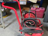 a red hand truck with a hose on it in a garage