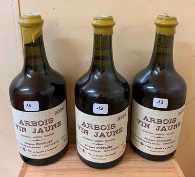 three bottles of wine sit on a wooden shelf in front of a wall