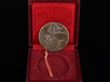 une vieille médaille d'argent dans une boîte rouge sur fond noir