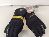une paire de gants noirs posée sur une surface blanche, avec une étiquette