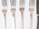 many forks and spoons laid out on a white surface