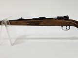 un fusil sur fond blanc, posé dans un support en verre transparent