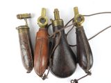 trois combinés téléphoniques anciens en laiton et cuir sont alignés sur une surface blanche