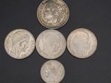 four different types of silver coins on a black surface