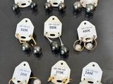 six paires de boucles d'oreilles en perles noires et blanches, avec leurs étiquettes de prix