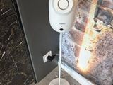 un haut-parleur blanc posé sur un pied, à côté d'une porte
