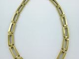 un collier en or composé de maillons carrés et de diamants sur fond blanc