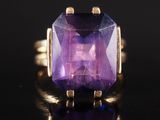 un gros plan d'une bague en pierre violette posée sur une surface noire