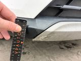 a person measuring the width of a car with a ruler