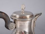 a silver tea pot with a handle on a table