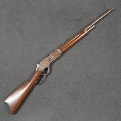 a rifle with a wooden handle on a gray surface