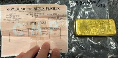 quelqu'un tient un morceau d'or à côté d'un lingot d'or
