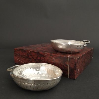 a silver bowl sitting next to a silver bowl on a wooden box