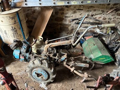 un tas de bric-à-brac dans un garage, avec des outils par terre