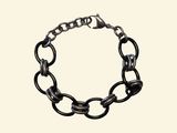 the chain bracelet is made of metal and has a black link