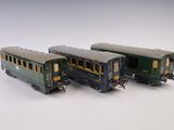 trois petits trains assis l'un à côté de l'autre sur une surface blanche