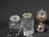 several glass jars and a glass candle holder on a black surface