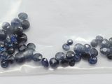 un sachet de saphirs bleus posé sur une surface blanche