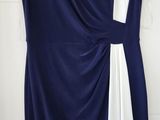 blue and white dress hanging on a hanger in front of a white wall
