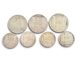 six silver coins are arranged in a row on a white surface