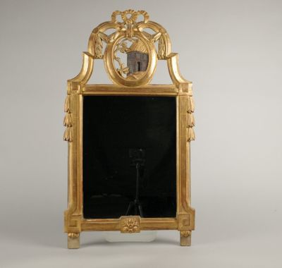 une image représentant un miroir à cadre doré sur lequel est posée une horloge