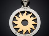 a close up of a silver and gold pendant with a sun
