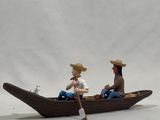 two figurines of a man and a woman in a boat